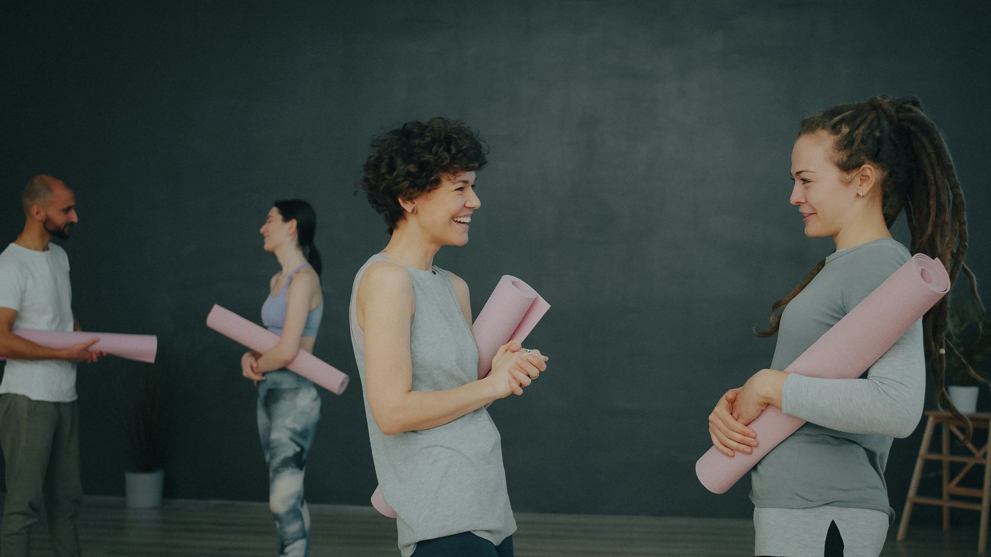 People holding rolled mats, chatting before class