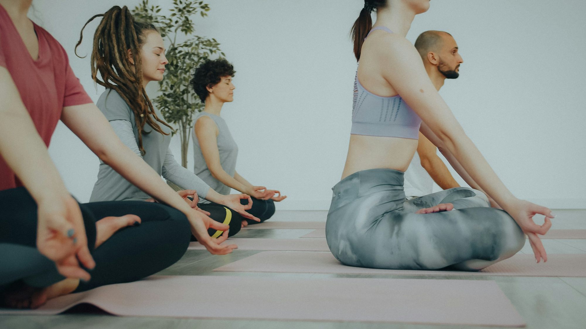 A class sitting cross-legged on mats with their eyes closed