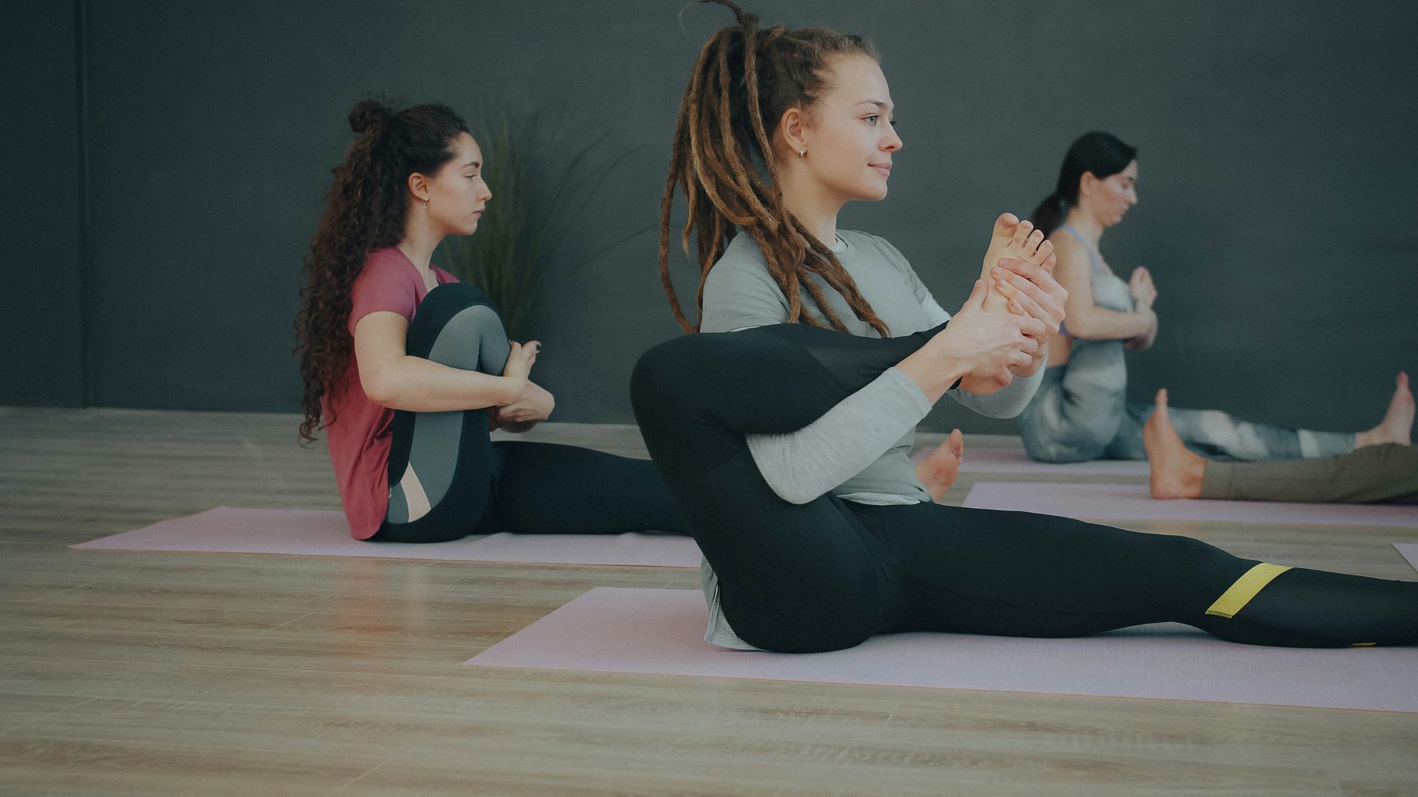 Two people seated on mats doing leg work