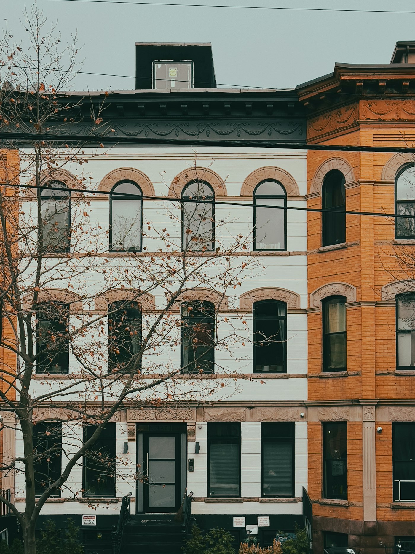 A three-story brick apartment building with bare trees in front