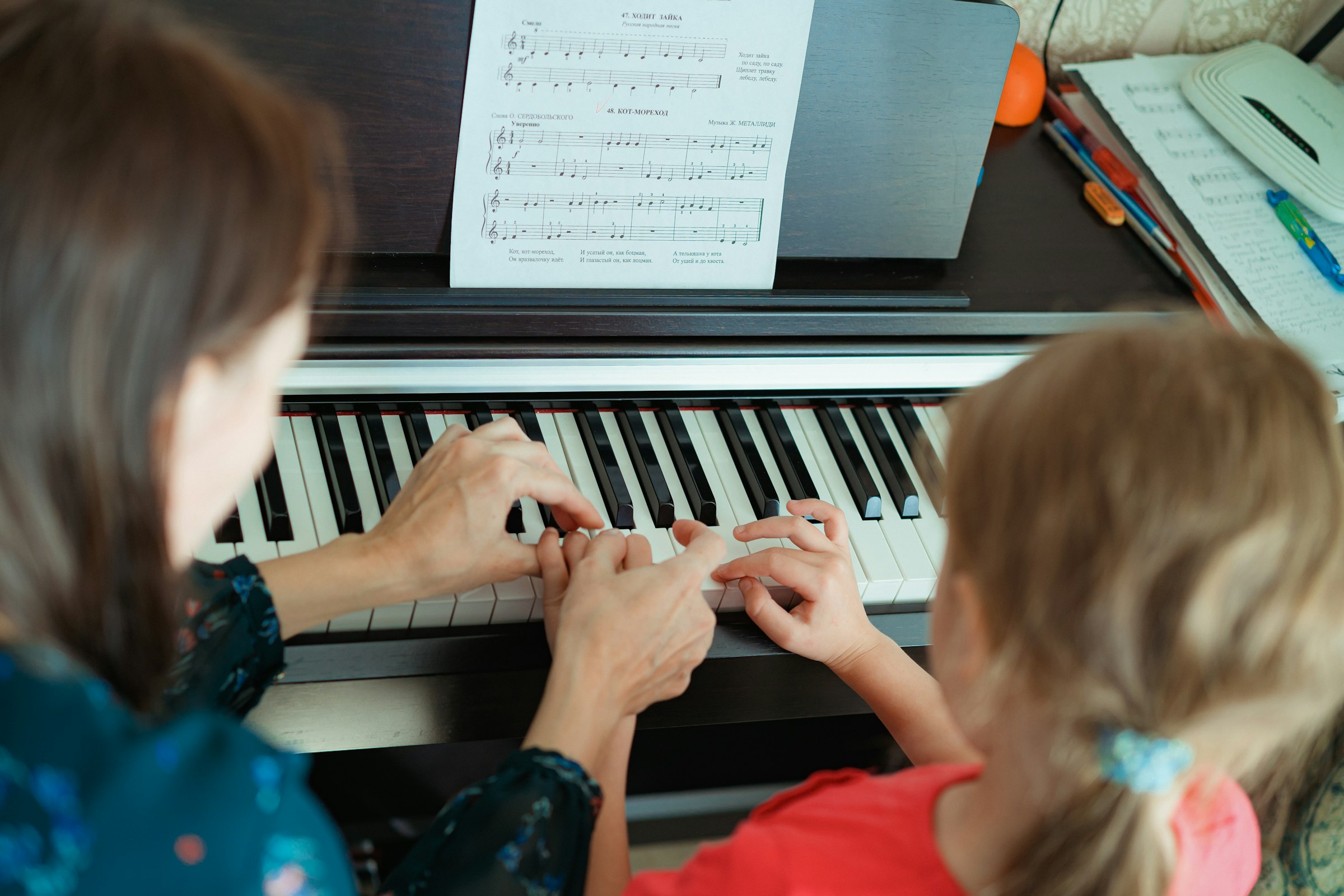 A teacher beside a young student at the piano during a weekly lesson