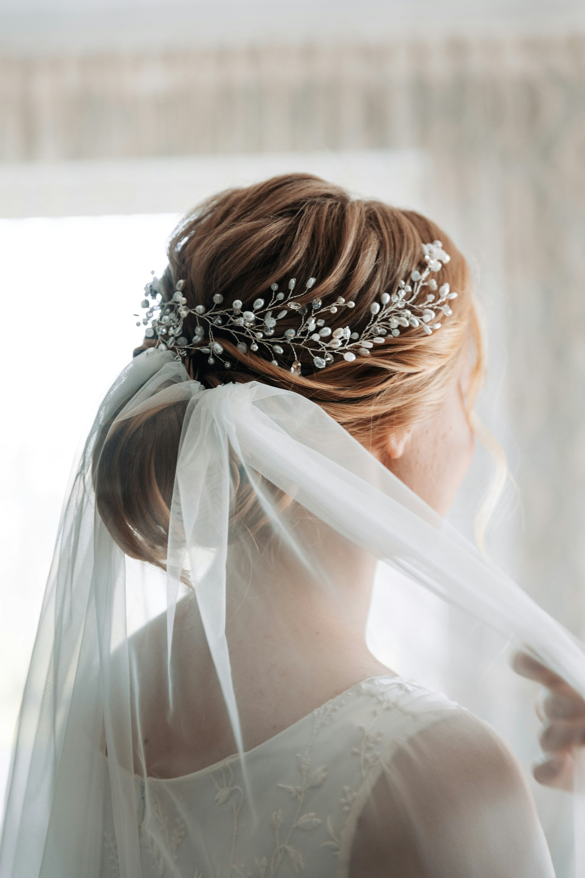 A low updo with pearl pins under a veil