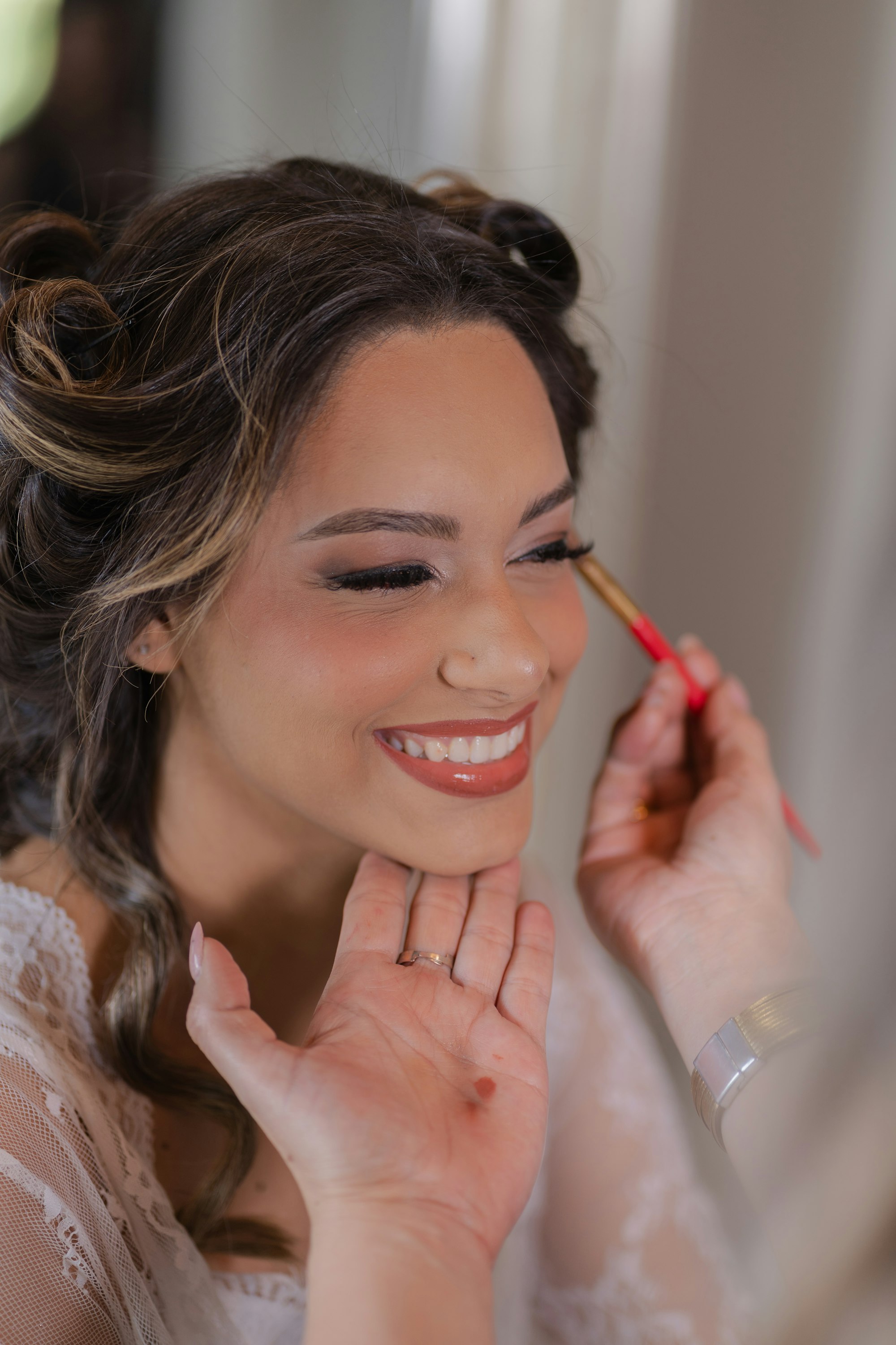 A bride laughing while Marisol sets her lashes