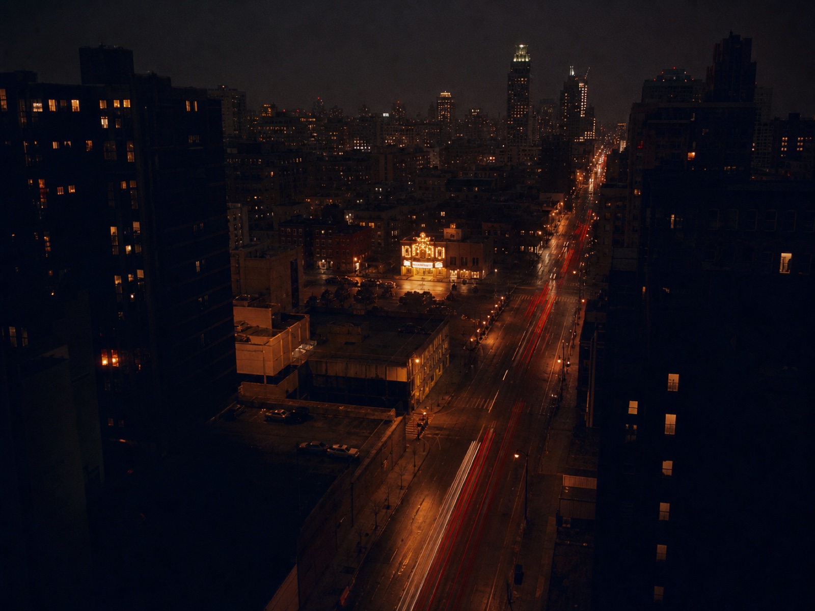 Woodward Avenue at night from a high window, tail lights streaking, the theatre marquee small and bright in the middle distance