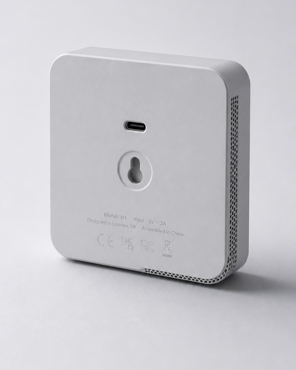 The rear face, showing the central USB-C port, moulded regulatory text and the wall-mount keyhole.