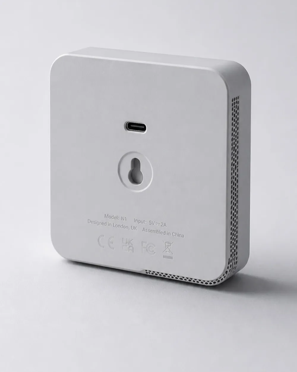 The rear face, showing the central USB-C port, moulded regulatory text and the wall-mount keyhole.