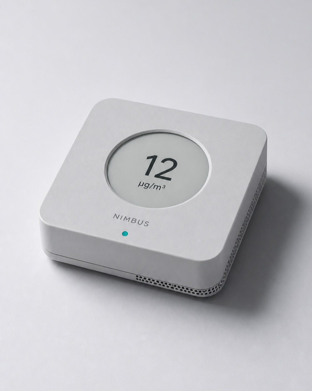 Nimbus One air quality monitor photographed at three-quarter angle against a cool grey sweep, its display reading 12 micrograms per cubic metre.