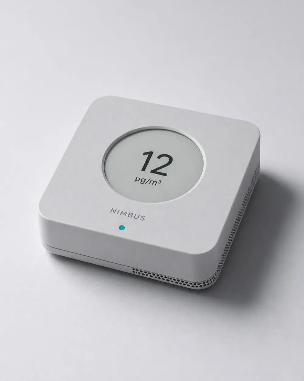 Nimbus One air quality monitor photographed at three-quarter angle against a cool grey sweep, its display reading 12 micrograms per cubic metre.