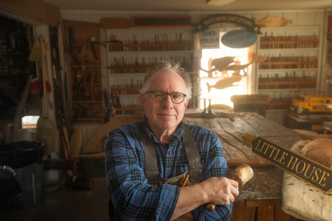 Nils Ostrander in his workshop, arms crossed, holding a mallet