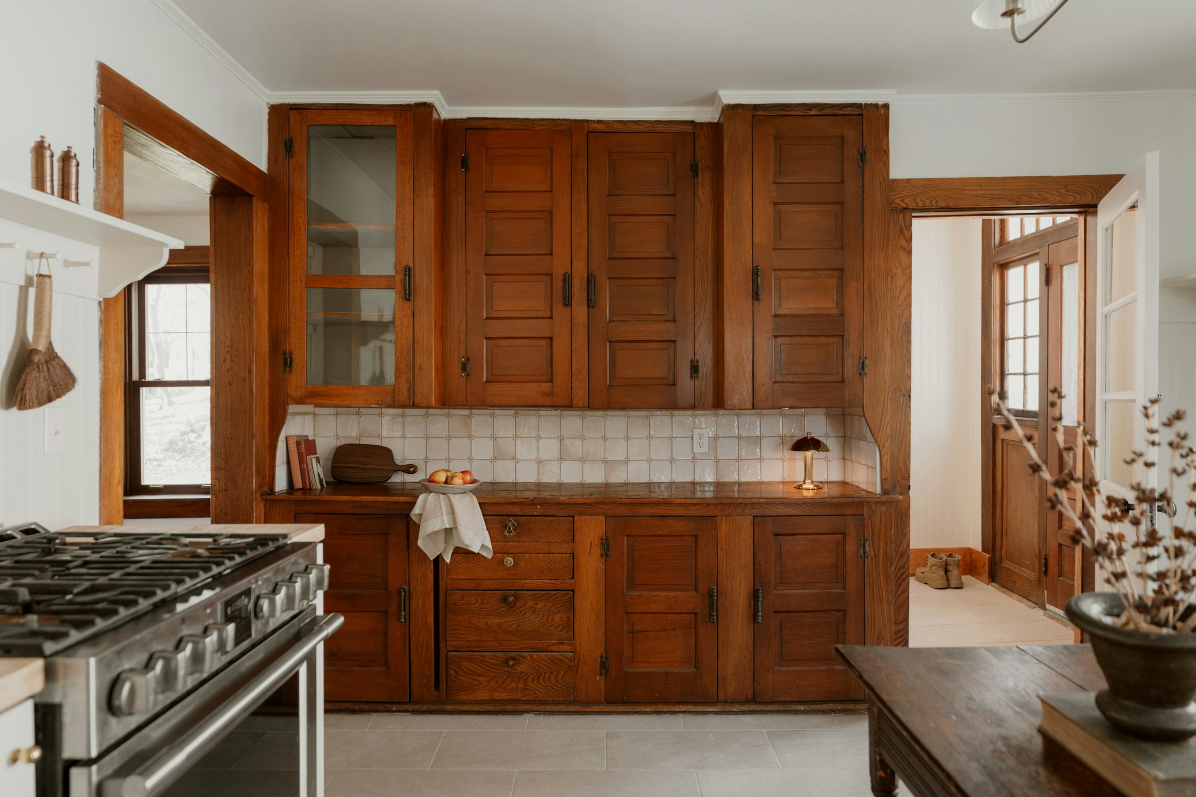 A restored kitchen in an old house: oak cabinets to the ceiling, a tiled backsplash and an old range