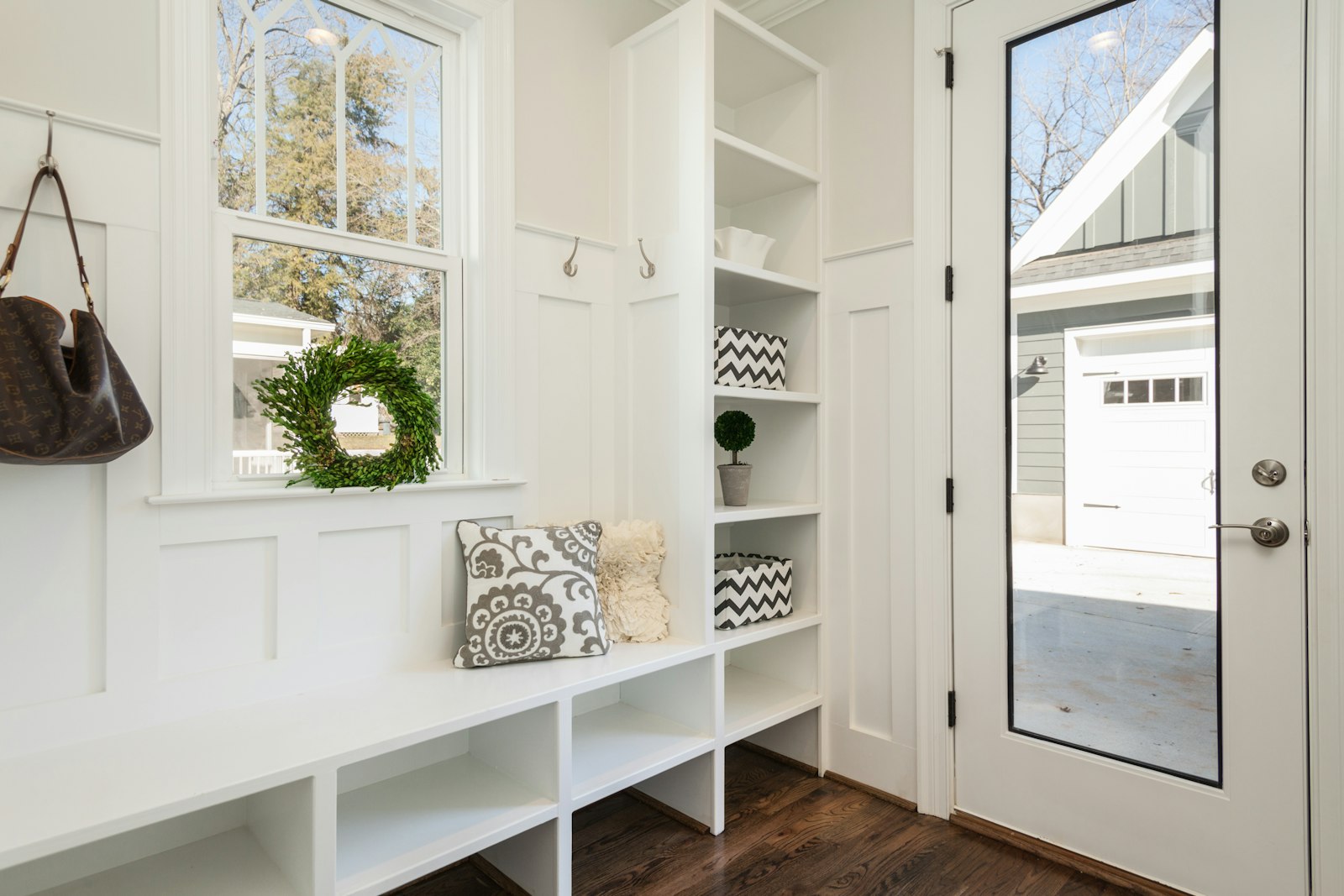 The finished mudroom: a white bench, cubbies and a half-glass back door