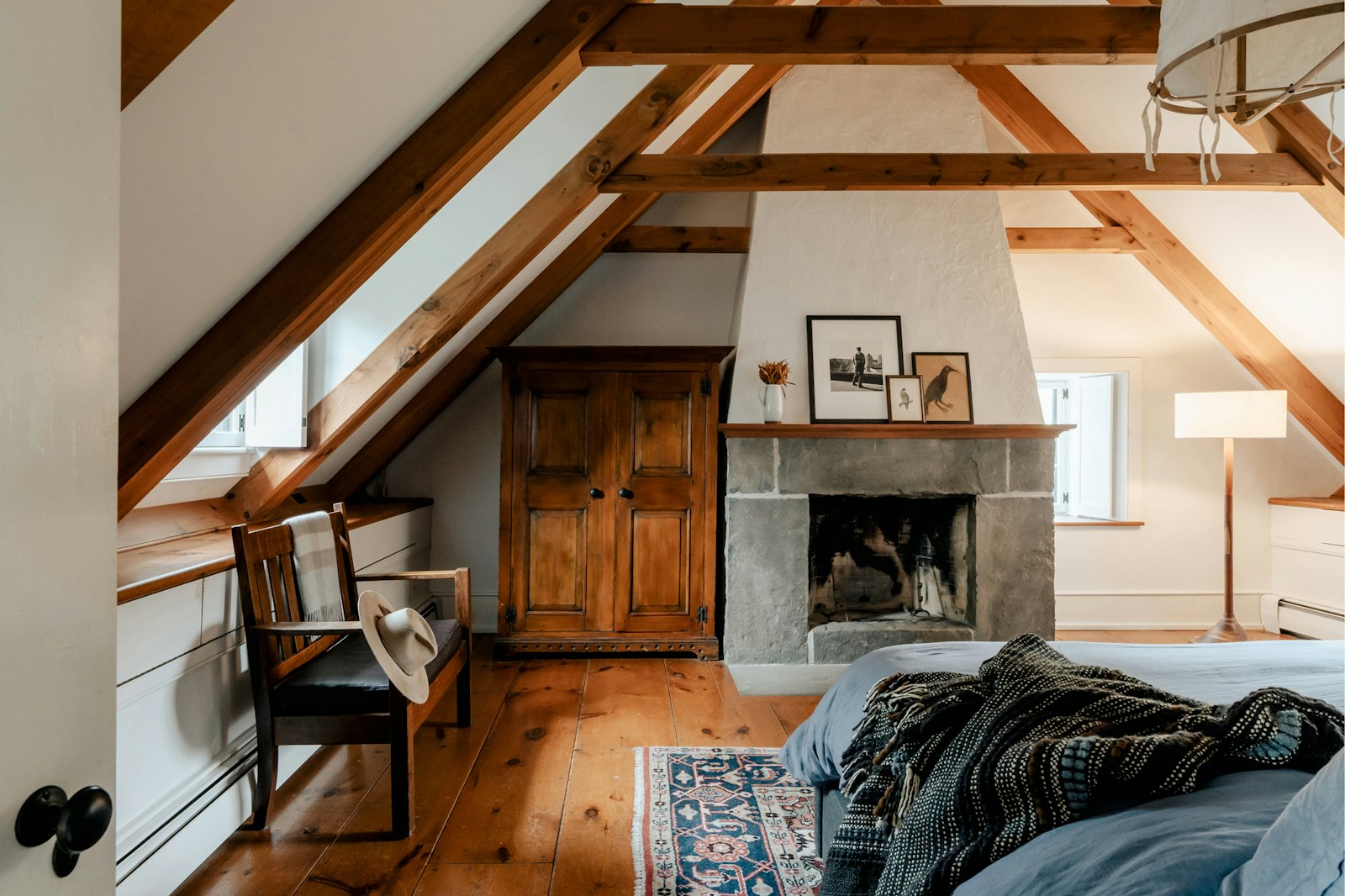 The Linden Hills attic bedroom with exposed beams and a stone fireplace