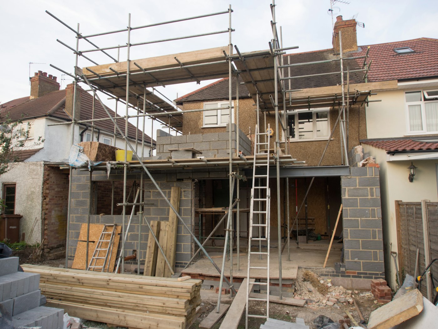 Mid-build: the addition framed and scaffolded against the back of the house