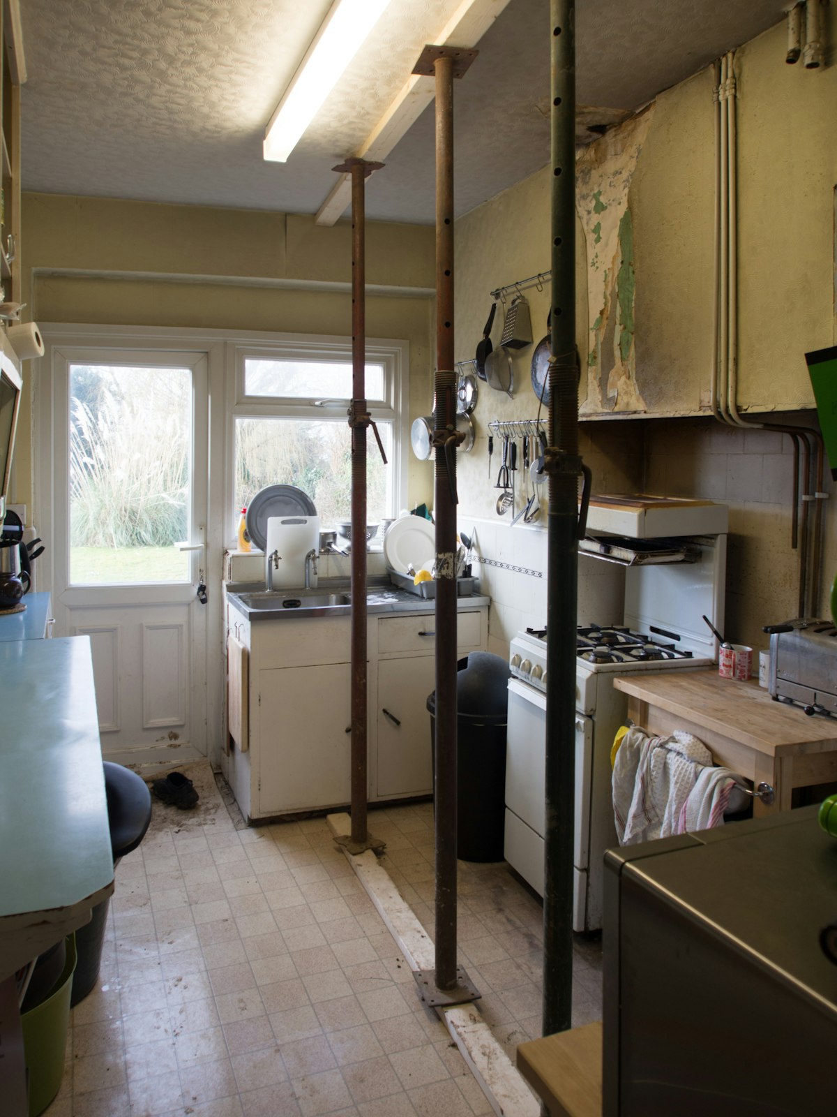 Before: a narrow galley kitchen with the door and window at the far end