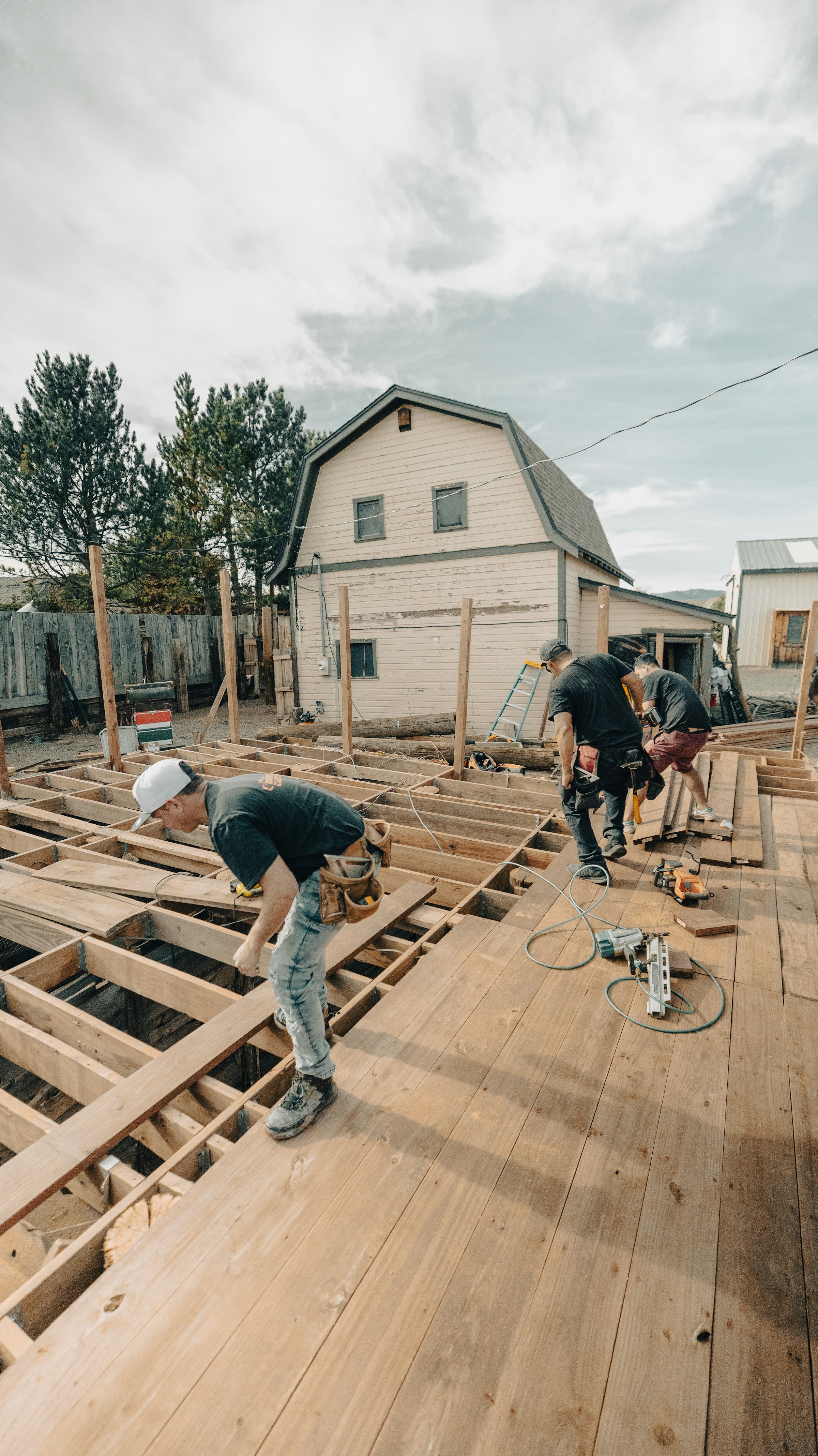 The crew framing a new floor beside an old gambrel-roofed house