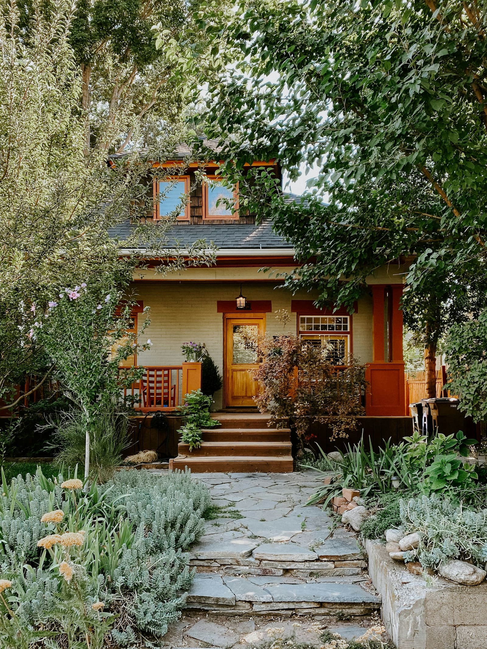 A craftsman bungalow with a deep porch behind a planted front garden