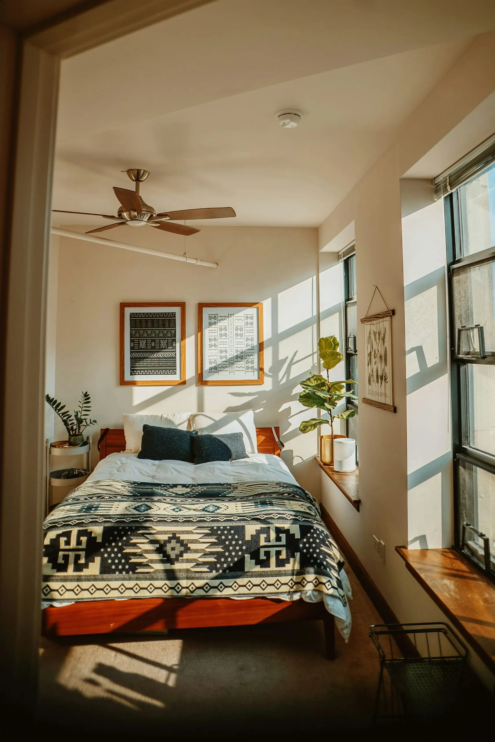 A bedroom with framed prints and morning light