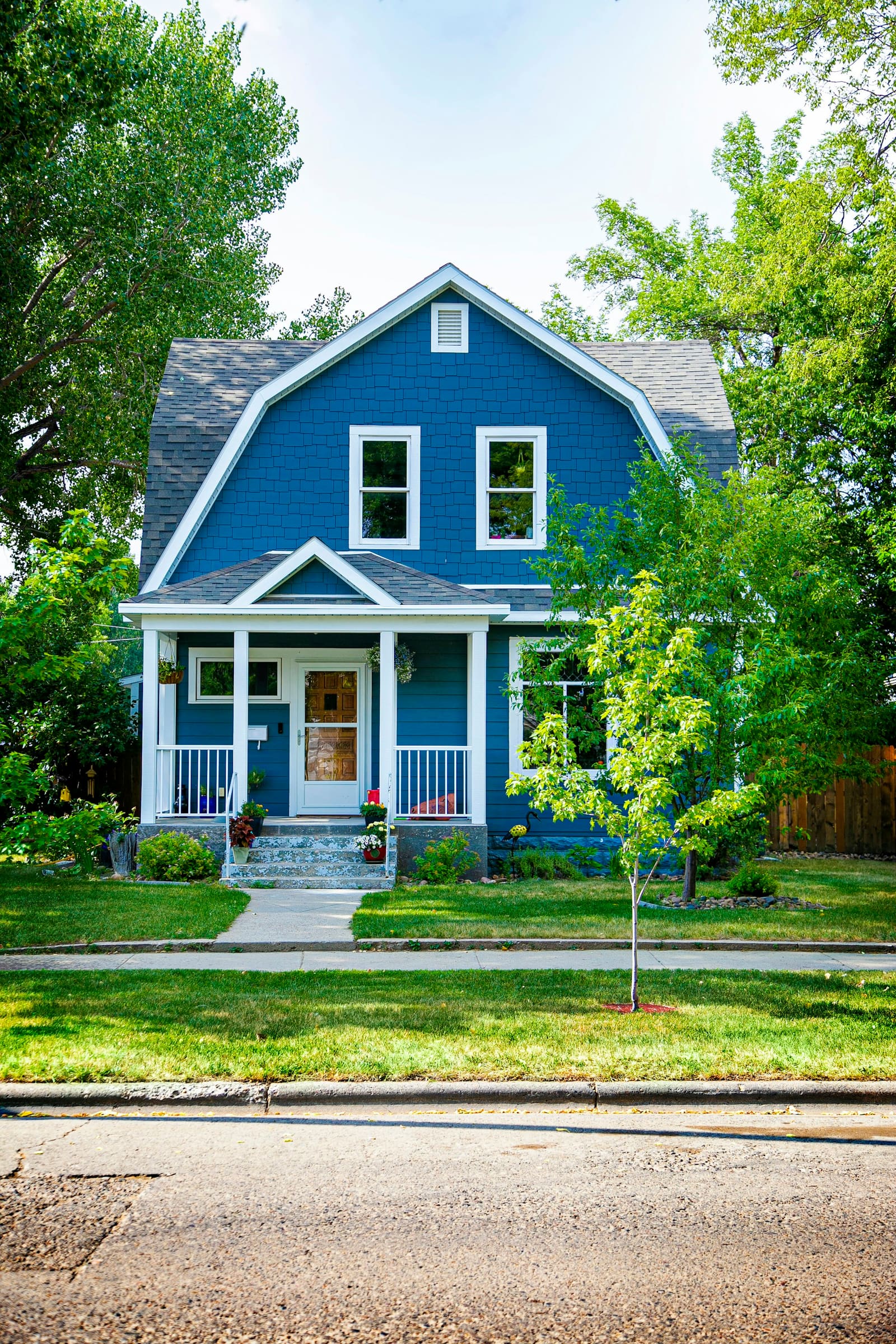 A blue gambrel-roofed house with a white porch