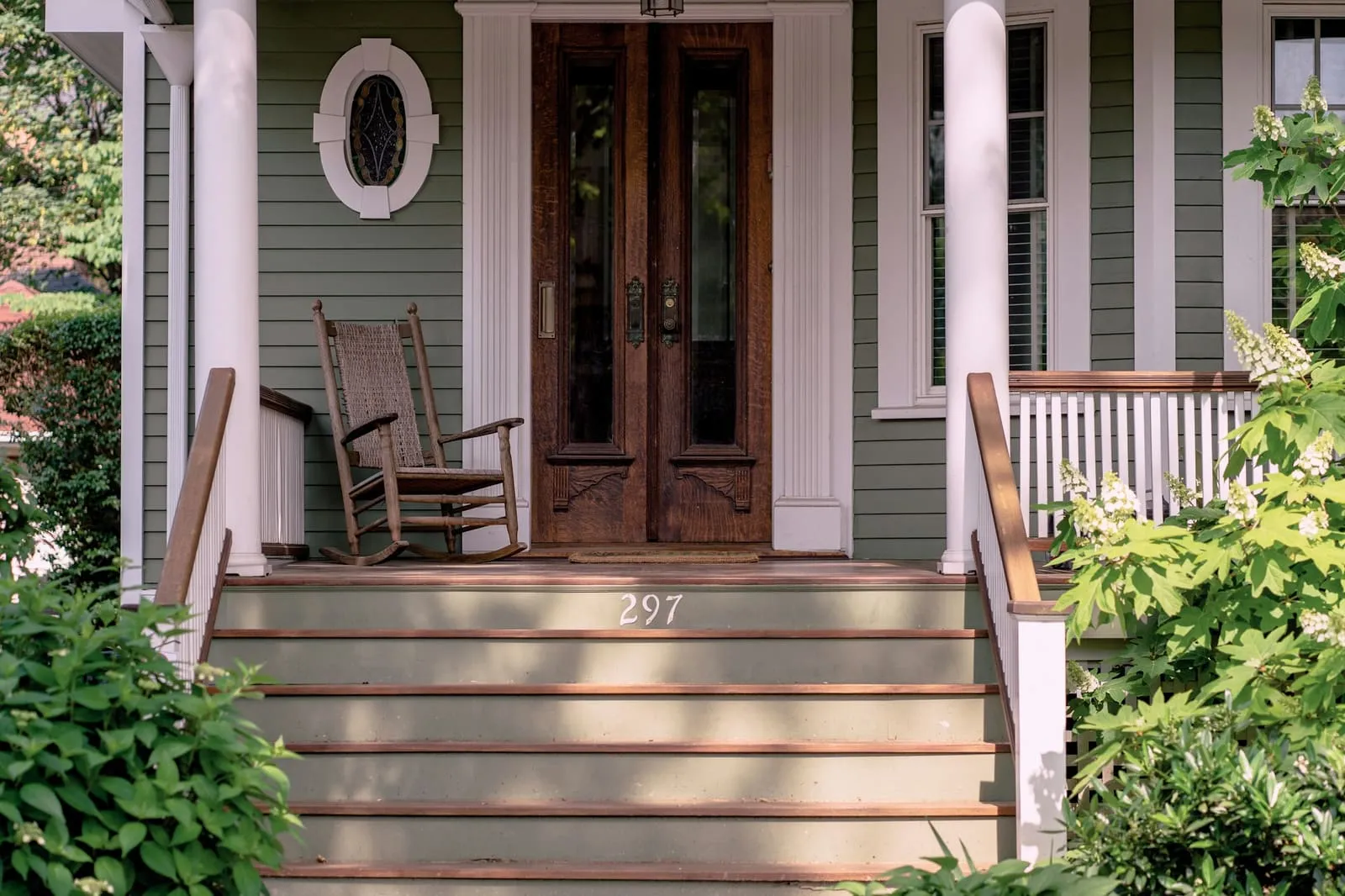Wooden steps up to a Victorian porch with tall double doors