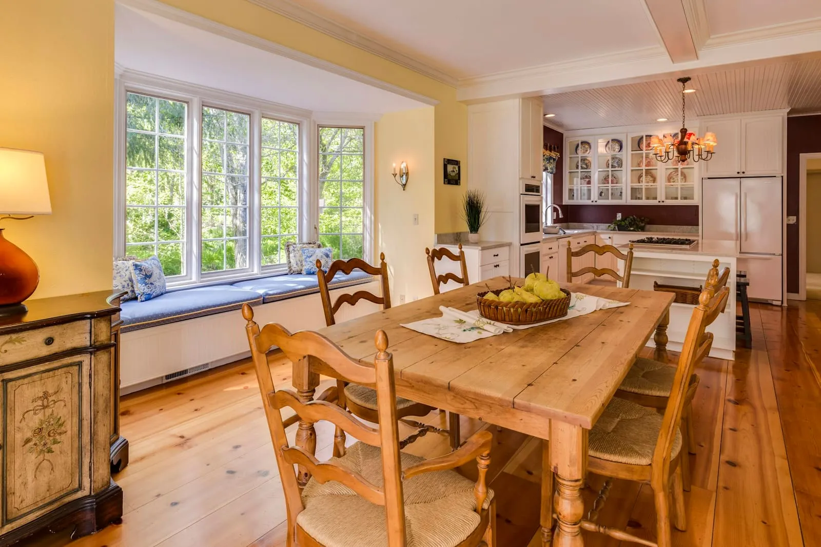 A dining room with a bay window and wood floors