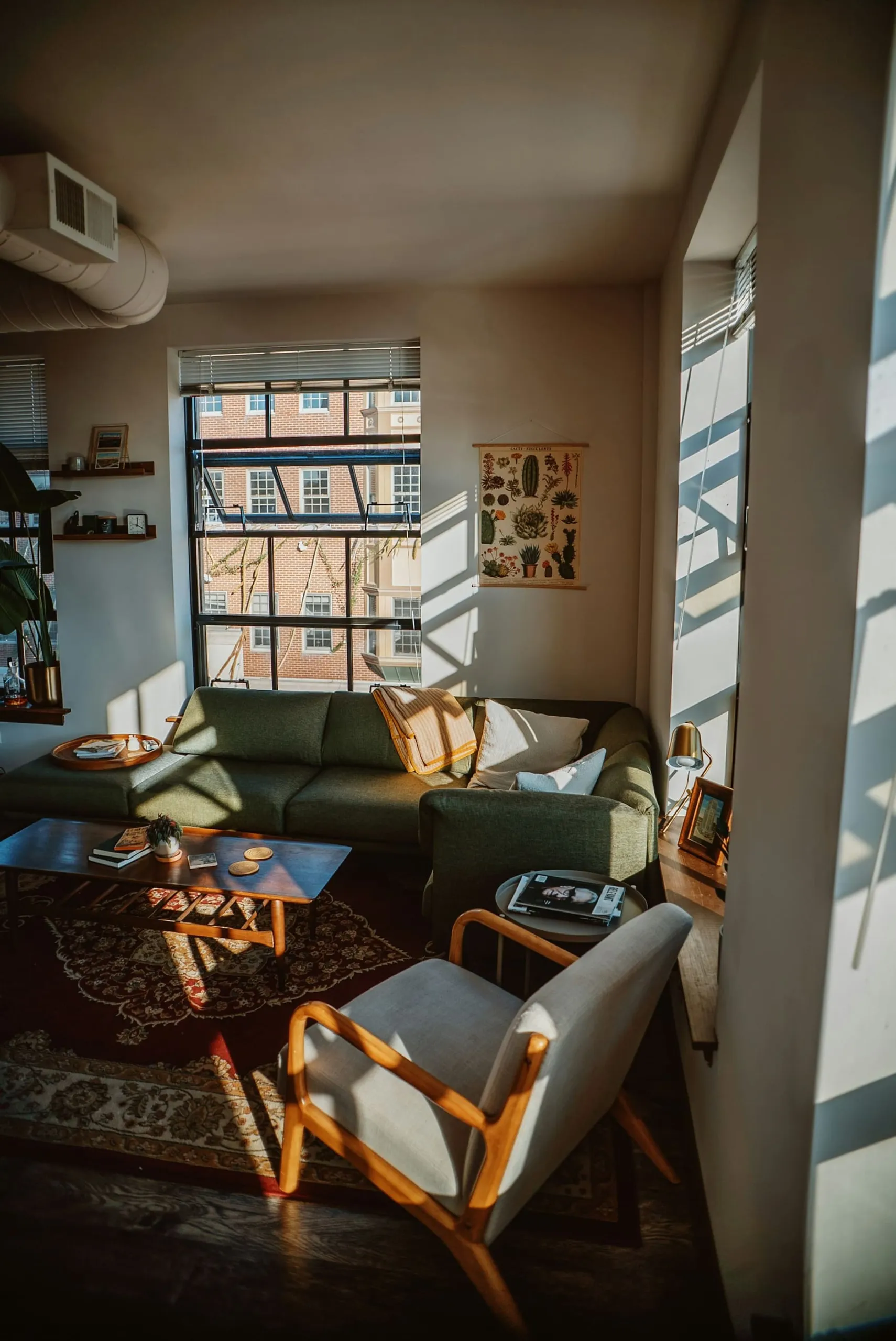 A sunny living room with a green sofa and tall windows