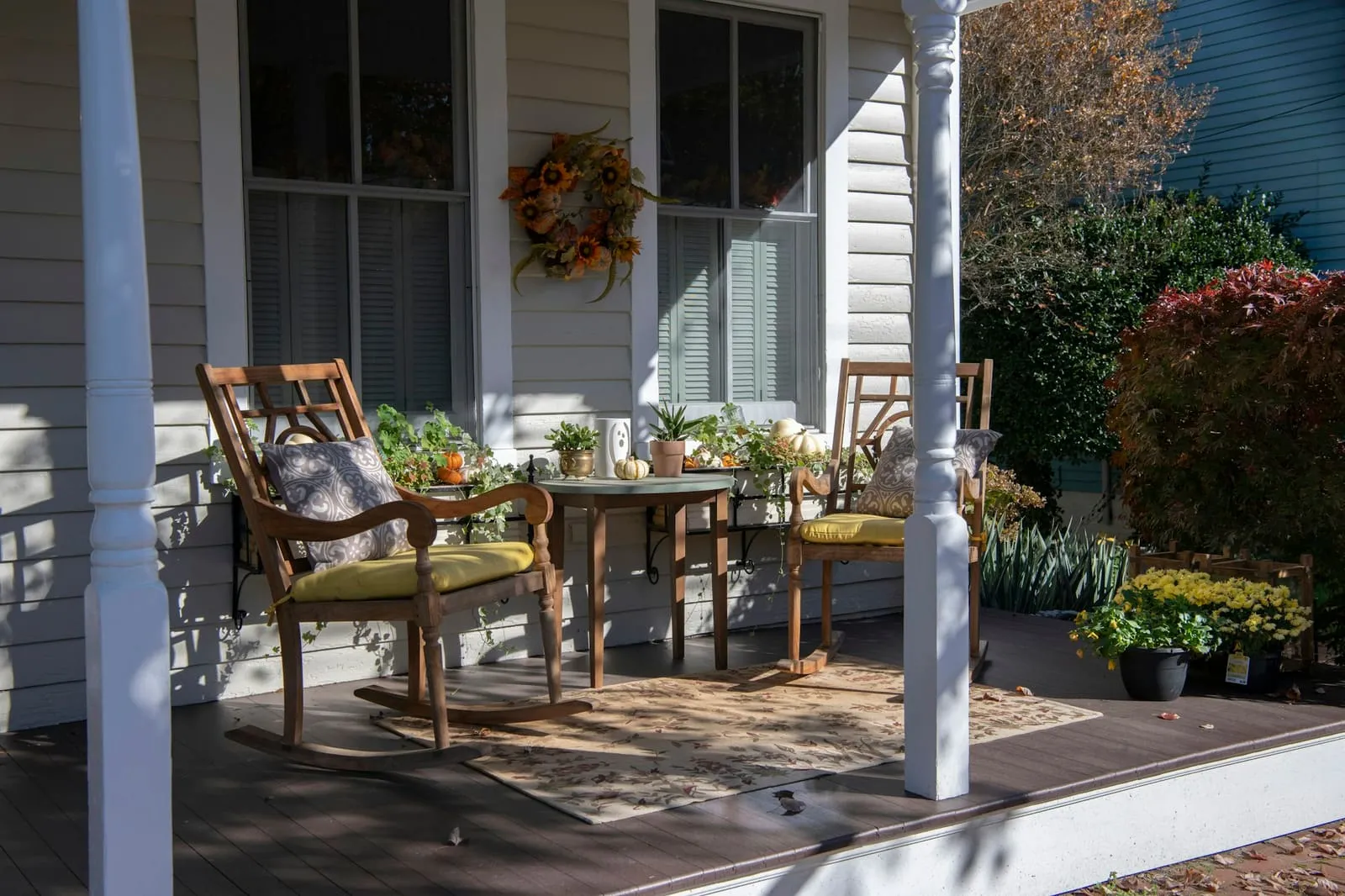 A front porch set with two chairs and a wreath on the door