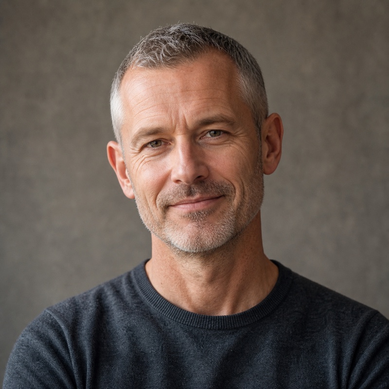 Square head-and-shoulders portrait of Tobias Renner, a man in his fifties with grey hair, soft plain background, natural daylight