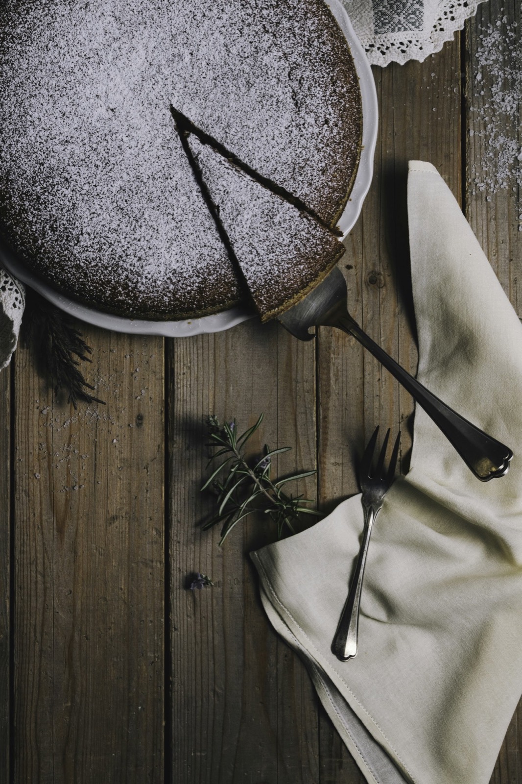 A dark chocolate cake dusted with sugar, one slice cut