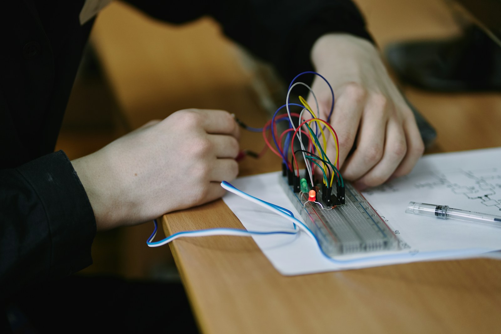 A student's hands wiring a circuit on a breadboard