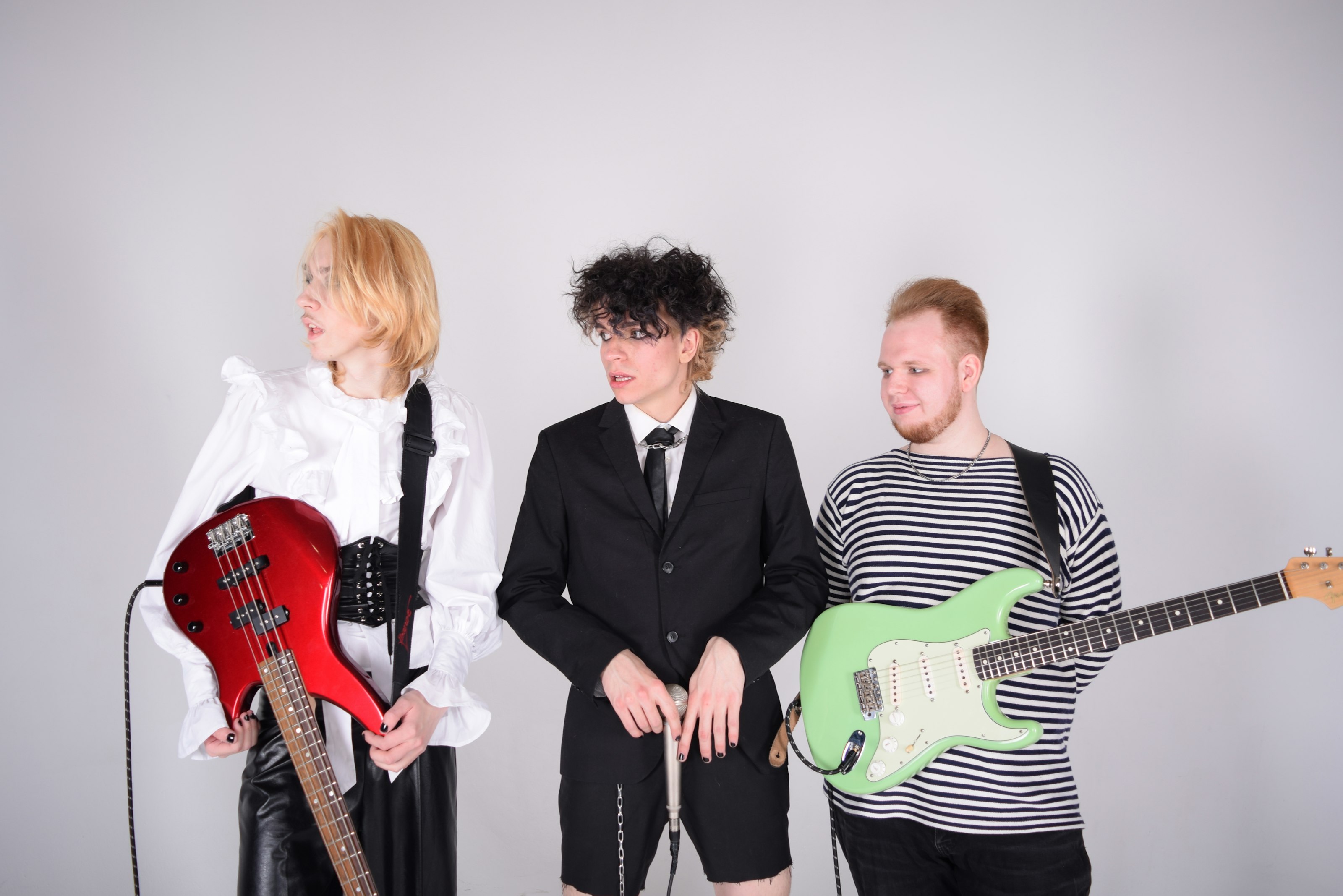 Bea, Sol and Tom standing with the red bass and the green guitar.