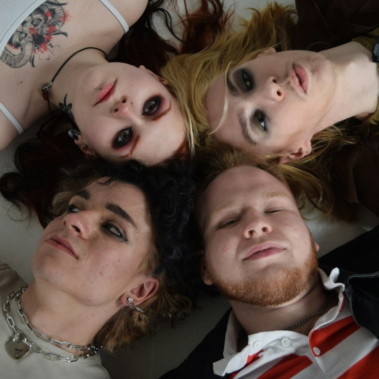 The cover of Leavers: the four members lying head to head on a white floor, photographed from above.