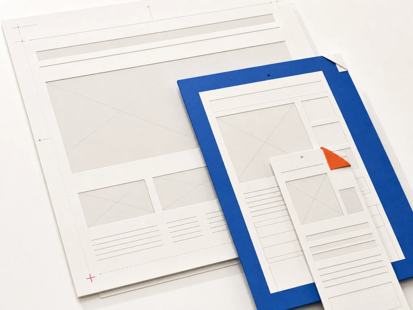 Layered paper website wireframes in desktop, tablet, and mobile proportions