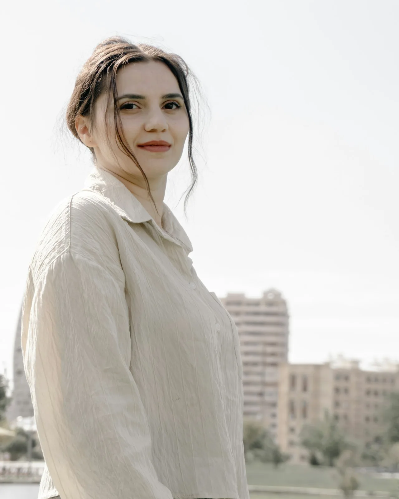 Elena Marsh standing outdoors in a pale linen shirt